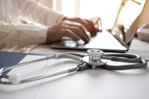 doctor working at computer fiduciary financial advisor for doctors