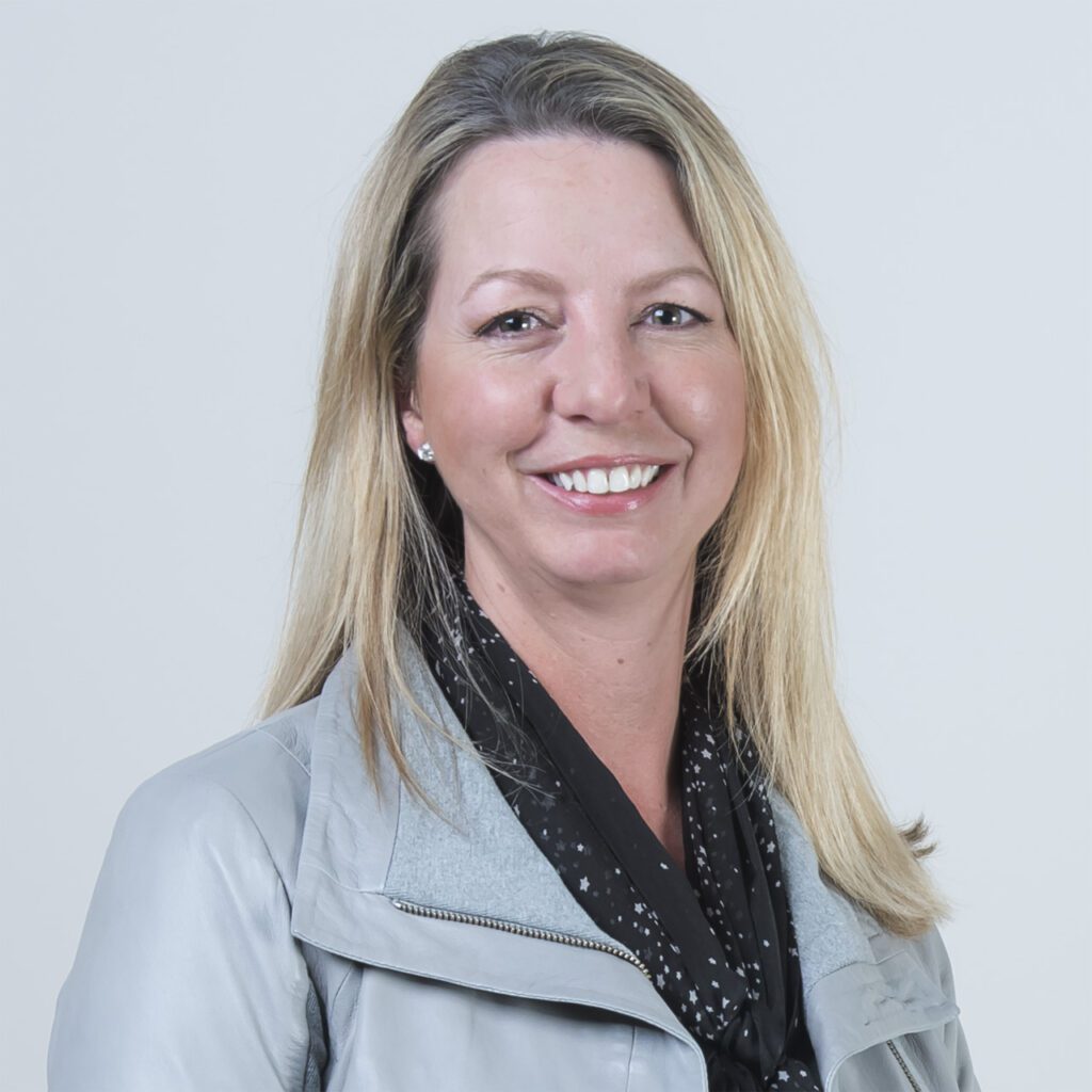 Portrait of Heather Anderson, a Brighton Jones client and board member of VertueLab, wearing a gray jacket and a black scarf.